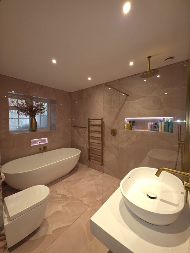 Luxury bathroom installation in Norwich with freestanding bath, walk-in shower, basin and tiled finish