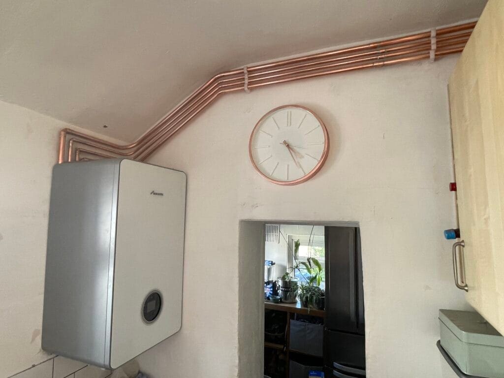 Worcester Bosch gas boiler installation with exposed copper pipework running neatly along the wall above a doorway
