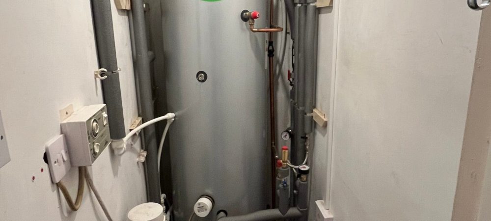 Hot water cylinder with expansion vessel, pipework and heating controls in a domestic airing cupboard