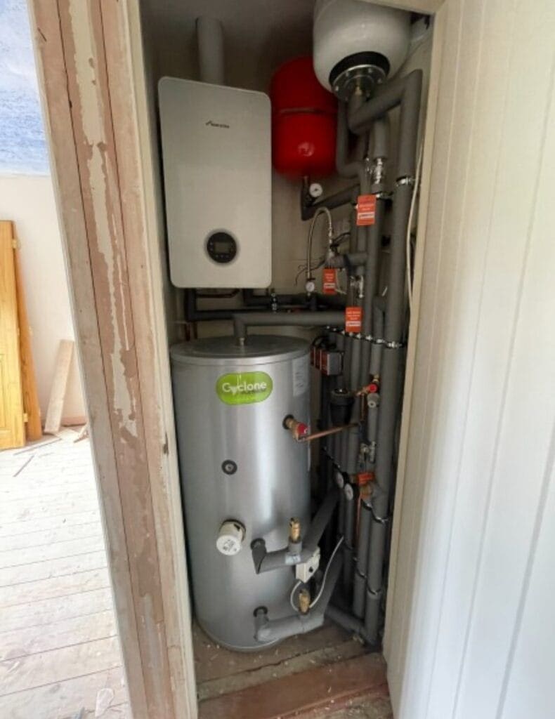 Heating engineer checking a hot water cylinder in a Downham Market home