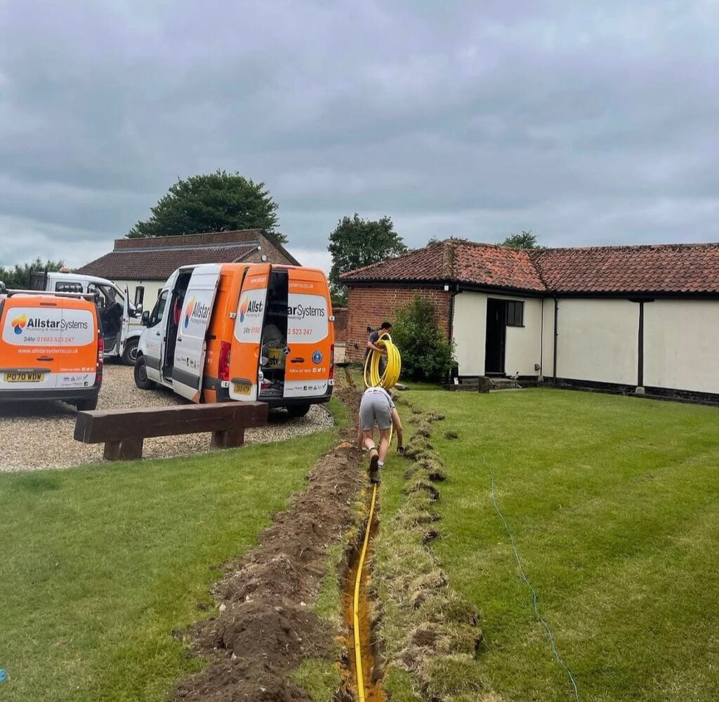 Allstar Systems engineers installing underground LPG gas pipework across a garden with company vans on site